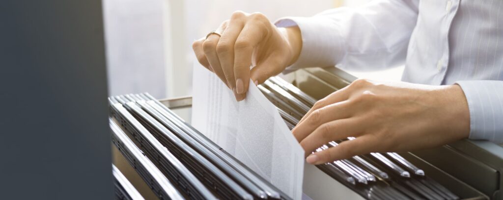 Close-up of hands storing files and paperwork in a filing cabinet