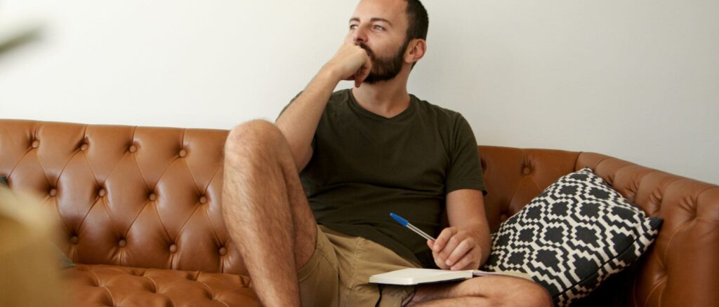 Young man looking thoughtful while he writes a letter to his loved ones