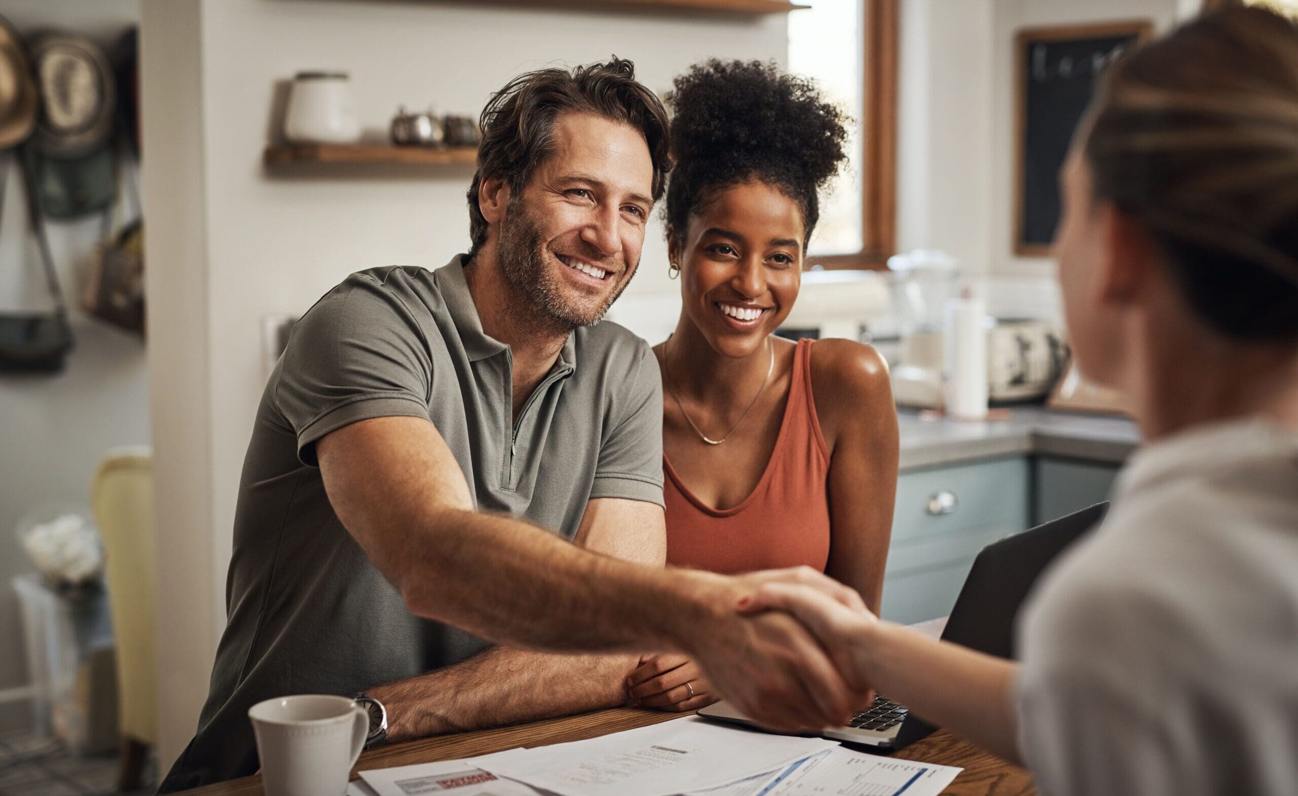 Young couple smiling and shaking hands with their advisor