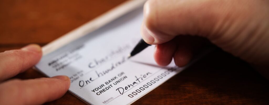 Close-up view of hand writing a donation cheque