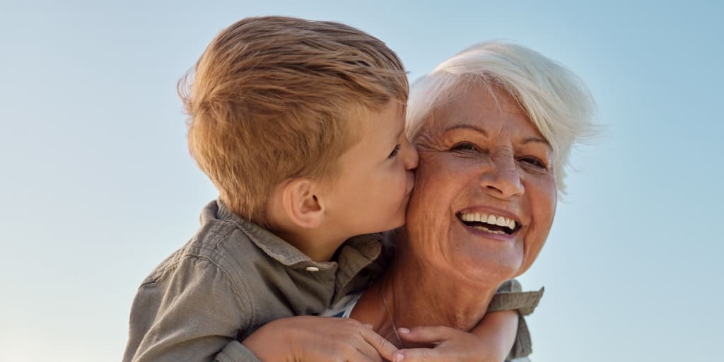 Grandson getting a piggy back ride and kissing his smiling grandmother on the cheek