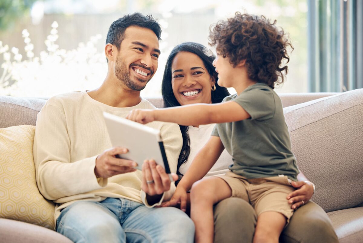 family with child, smiling while sitting on a couch