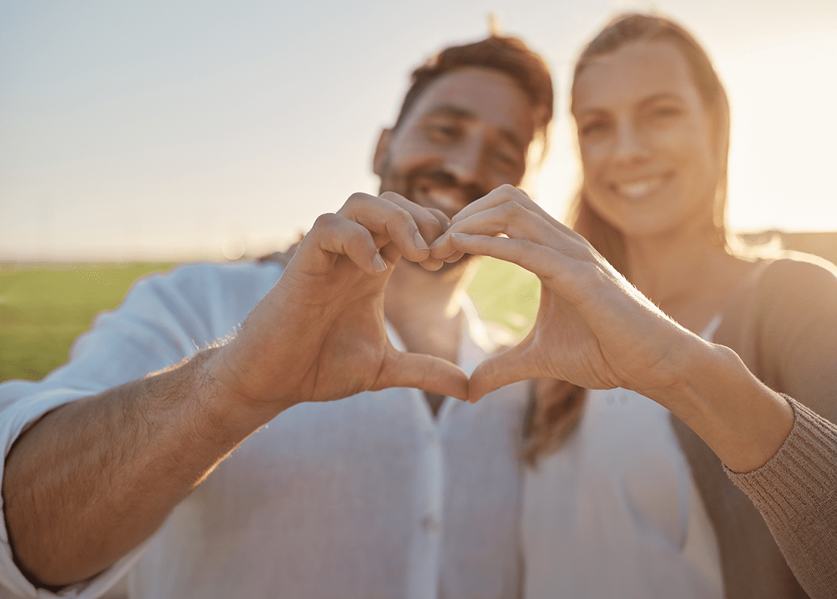 Couple making heart with hands as they smile at camera