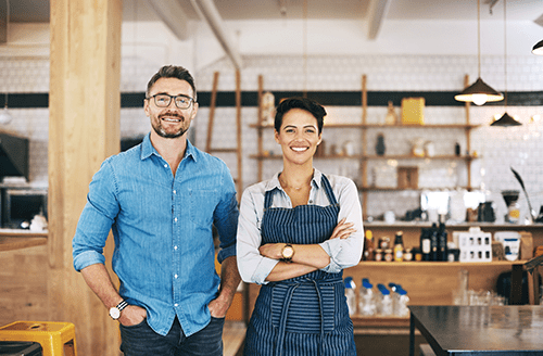 Business partners standing in their shop and smiling at the camera