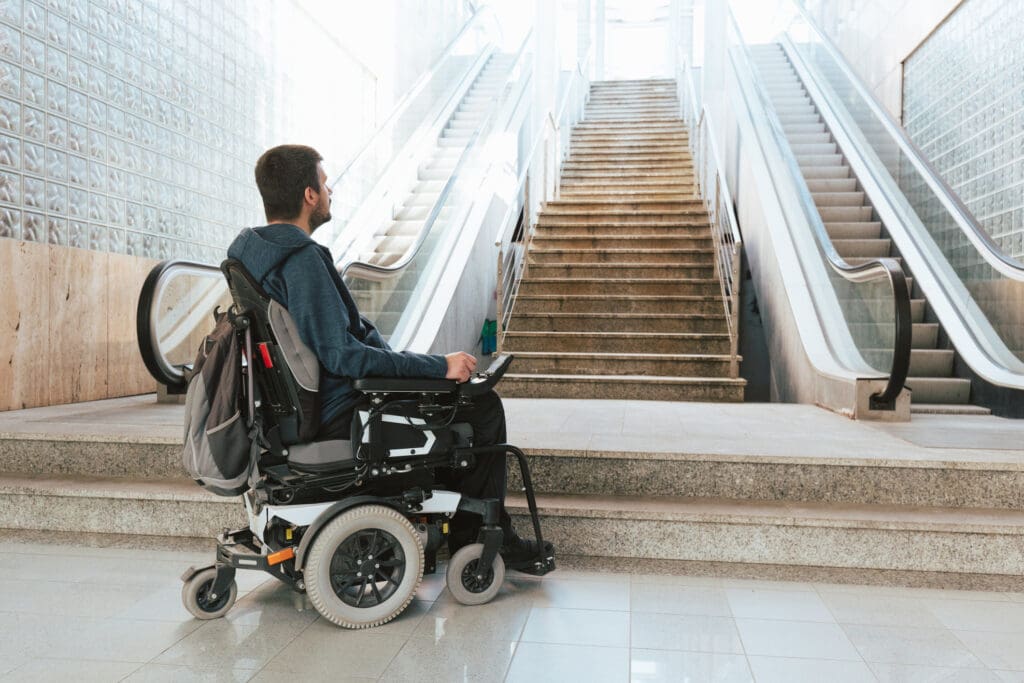 Man in wheelchair at bottom of stairs, staring up