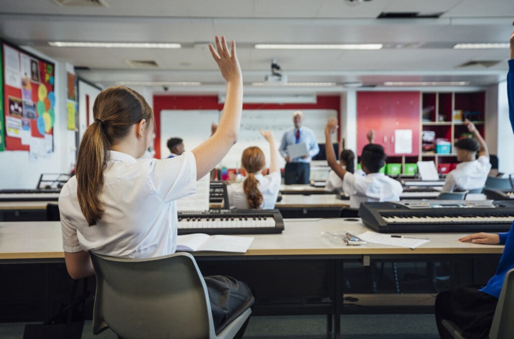 Back view of students with hands raised in music class